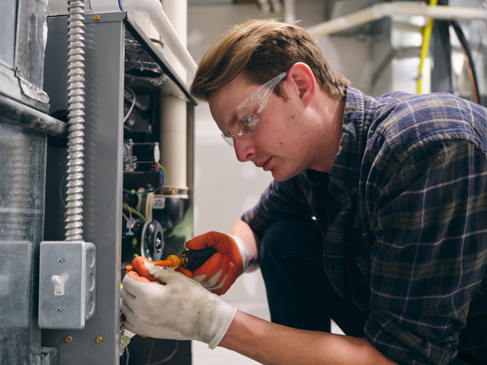 A repairman working inside a home, repairing a furnace